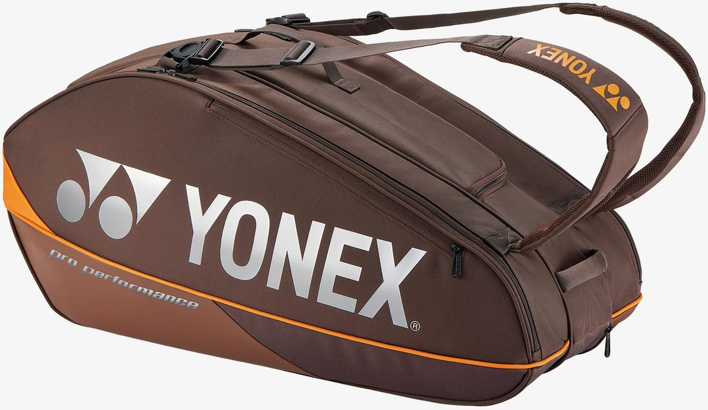 The Yonex 92429EX 9 Racket Pro Tennis Bag in Espresso Brown features bold orange accents, white “YONEX” branding, and comfortable shoulder straps. Designed to conveniently carry your tennis gear, this spacious bag offers multiple compartments for up to nine rackets.