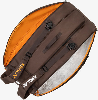 The Yonex 92429EX 9 Racket Pro Tennis Bag in Espresso Brown features orange lining, an insulated compartment, two shoulder straps, side handles, and multiple zippered pockets. Shown unzipped and open on a white background, this spacious Yonex bag is designed to hold up to nine rackets and provides ample storage for all your tennis gear.