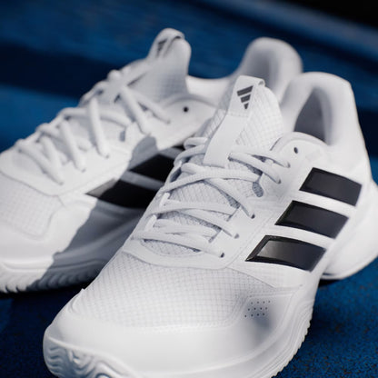 A pair of adidas Gamecourt 3 Men's Tennis Shoes in Cloud White/Core Black, featuring black side stripes, white laces, and a lightweight mesh upper with a sporty design, are displayed on a blue surface.