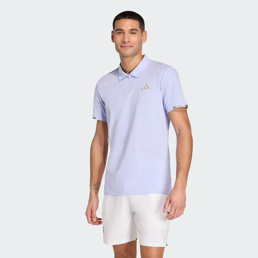 A man wearing an adidas Climacool Mens Tennis Polo Shirt in Violet Tone and white shorts stands against a plain light background, smiling at the camera.