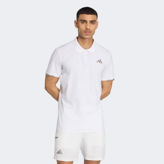 A man stands with his hands behind his back against a light gray background, wearing an adidas Climacool Mens Tennis Polo Shirt in white and matching shorts, both featuring the adidas logo.