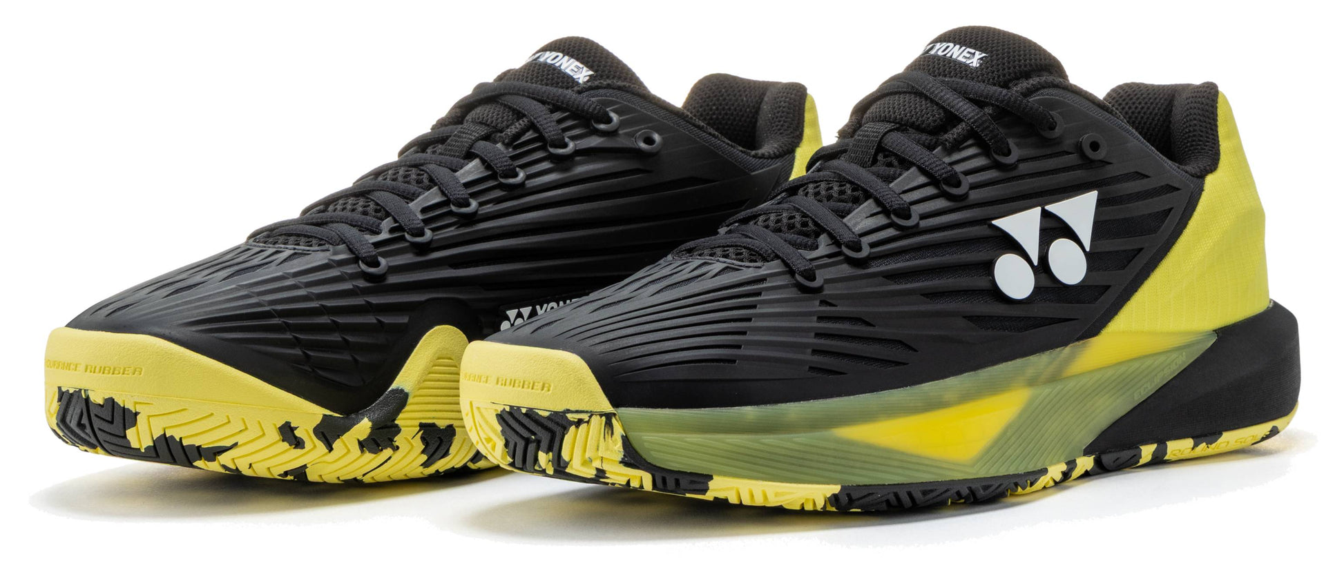 A pair of Yonex Power Cushion Eclipsion 5 Men’s Tennis Shoes in black and yellow, featuring the Yonex logo in white, black laces, and patterned yellow soles, are placed side by side on a white background.