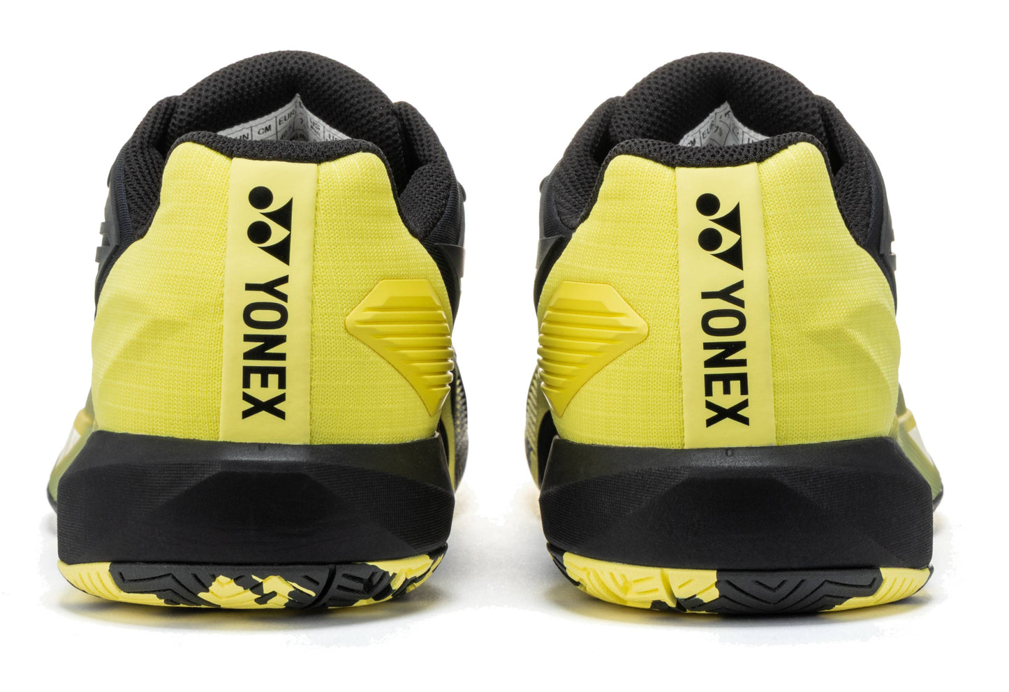 Here’s a rewritten version using the given product data: The Yonex Power Cushion Eclipsion 5 Men’s Tennis Shoes in black and yellow are shown from the back, displaying the Yonex logo and name printed vertically on the heel. These men’s tennis shoes feature Yonex Power Cushion technology to provide enhanced comfort and stability on the court.