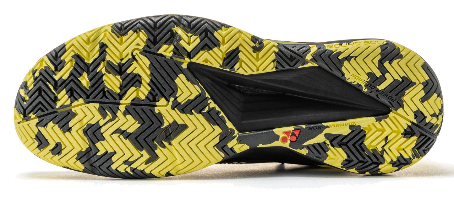 The image displays the black and yellow patterned sole of the Yonex Power Cushion Eclipsion 5 Men’s Tennis Shoes by Yonex, featuring an intricate combination of zigzag and herringbone tread patterns for superior traction. The sole includes text indicating “Round Sole” and “Non-Marking,” emphasizing the shoe’s focus on grip and stability, which are key qualities in high-performance tennis footwear.