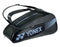 The Yonex 82426EX Active 6 Racket Tennis Bag in black, adorned with white and blue accents and the Yonex logo, includes two shoulder straps and a handy shoe compartment.