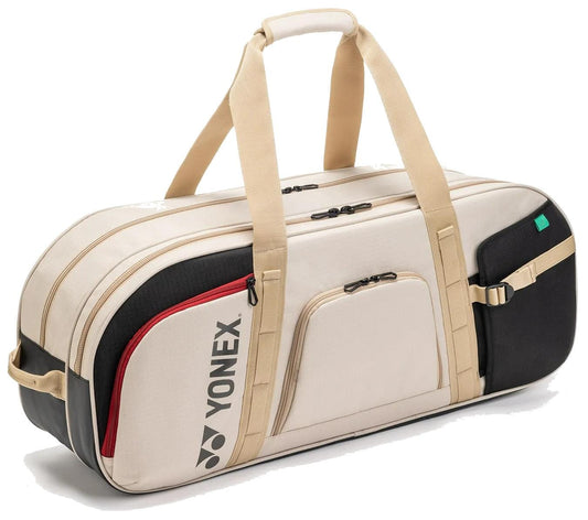 The Yonex BA72631WEX Gearlogic Tournament Tennis Bag in beige features multiple zippered compartments, tan handles and straps, and the Yonex logo—ideal for tournaments.