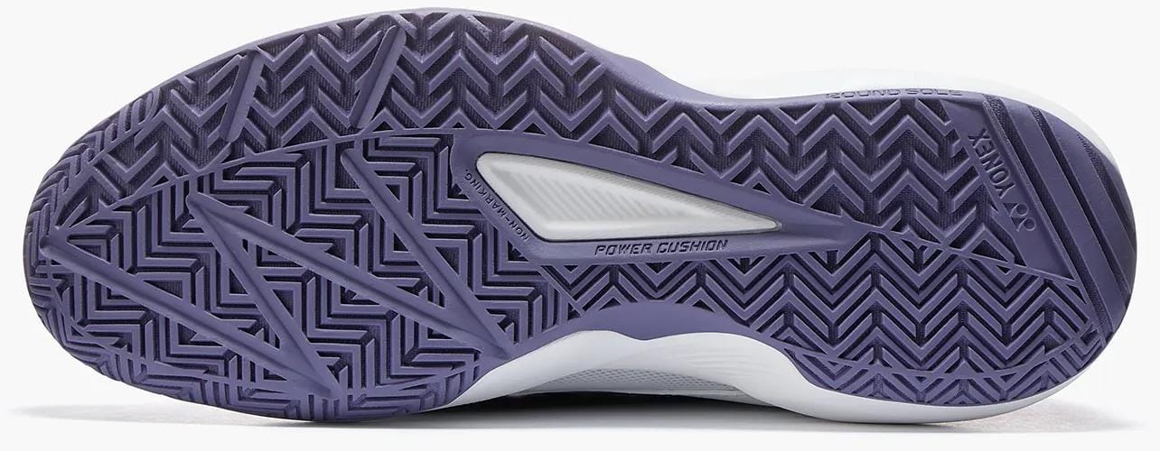 The image shows the white and sax sole of Yonex Pro-Move Classic Mens Tennis Shoes, featuring a zigzag tread pattern and "Power Cushion" printed on the arch, showcasing Yonex's Power Cushion technology.
