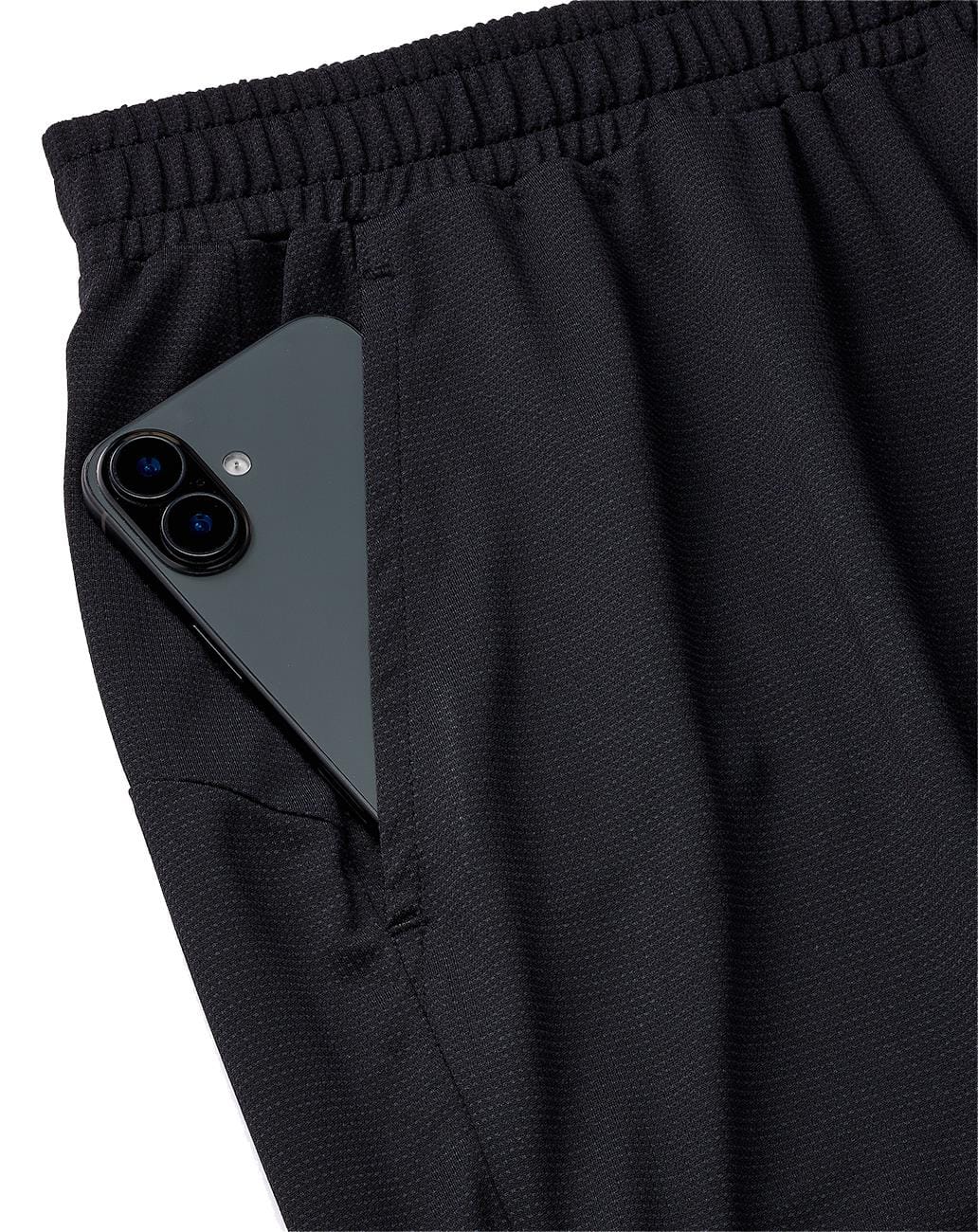 A black smartphone is partially tucked into the right pocket of Yonex 15239YX Knit Men's Tennis Shorts - Black by Yonex, featuring an elastic waistband.