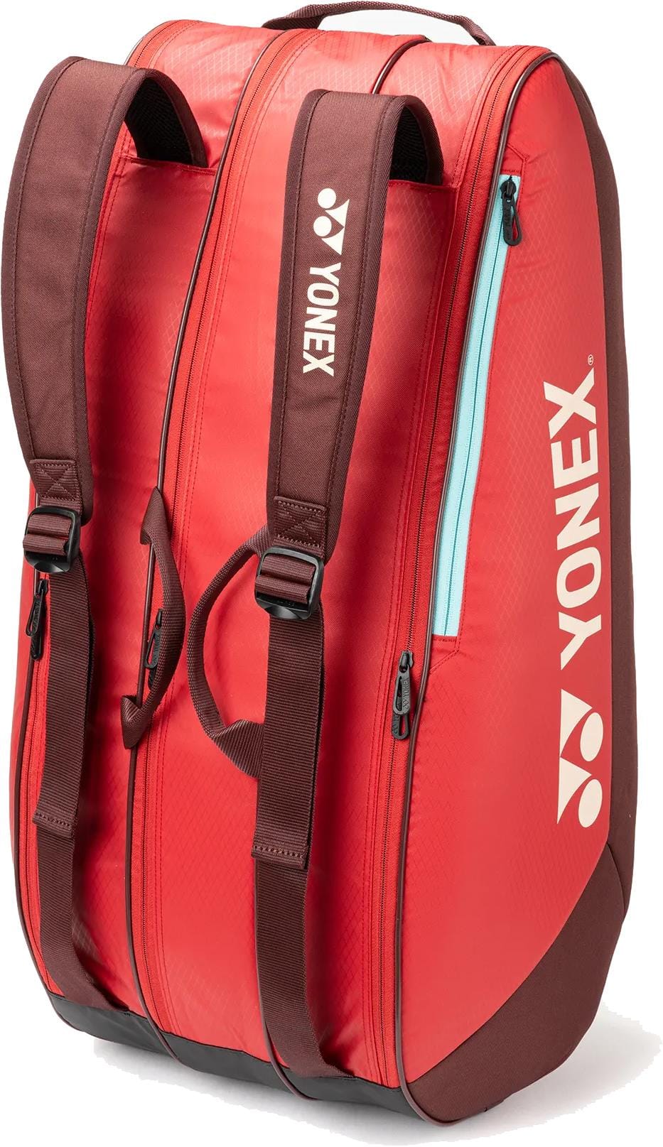 The Yonex 42529EX Team 9 Racket Tennis Bag in Ruby Red features maroon straps and handles, white Yonex logo and name, multiple zippered compartments, and holds up to 9 rackets.