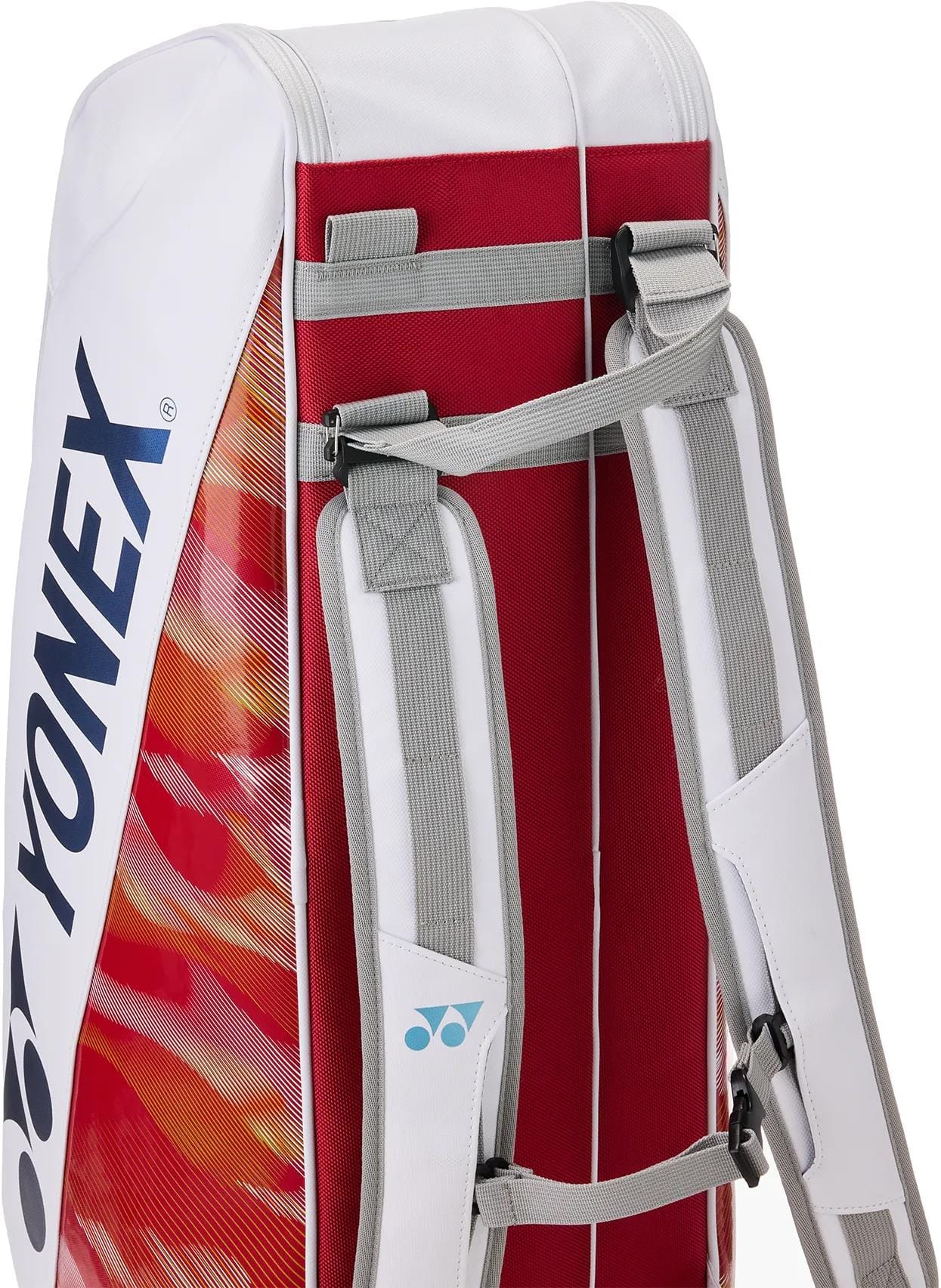 A close-up of the Yonex 02626EX Expert 6 Racket Tennis Bag in white, featuring red accents, gray padded shoulder straps, a flame-like orange design, and space for up to 6 rackets with thermoguard protection.