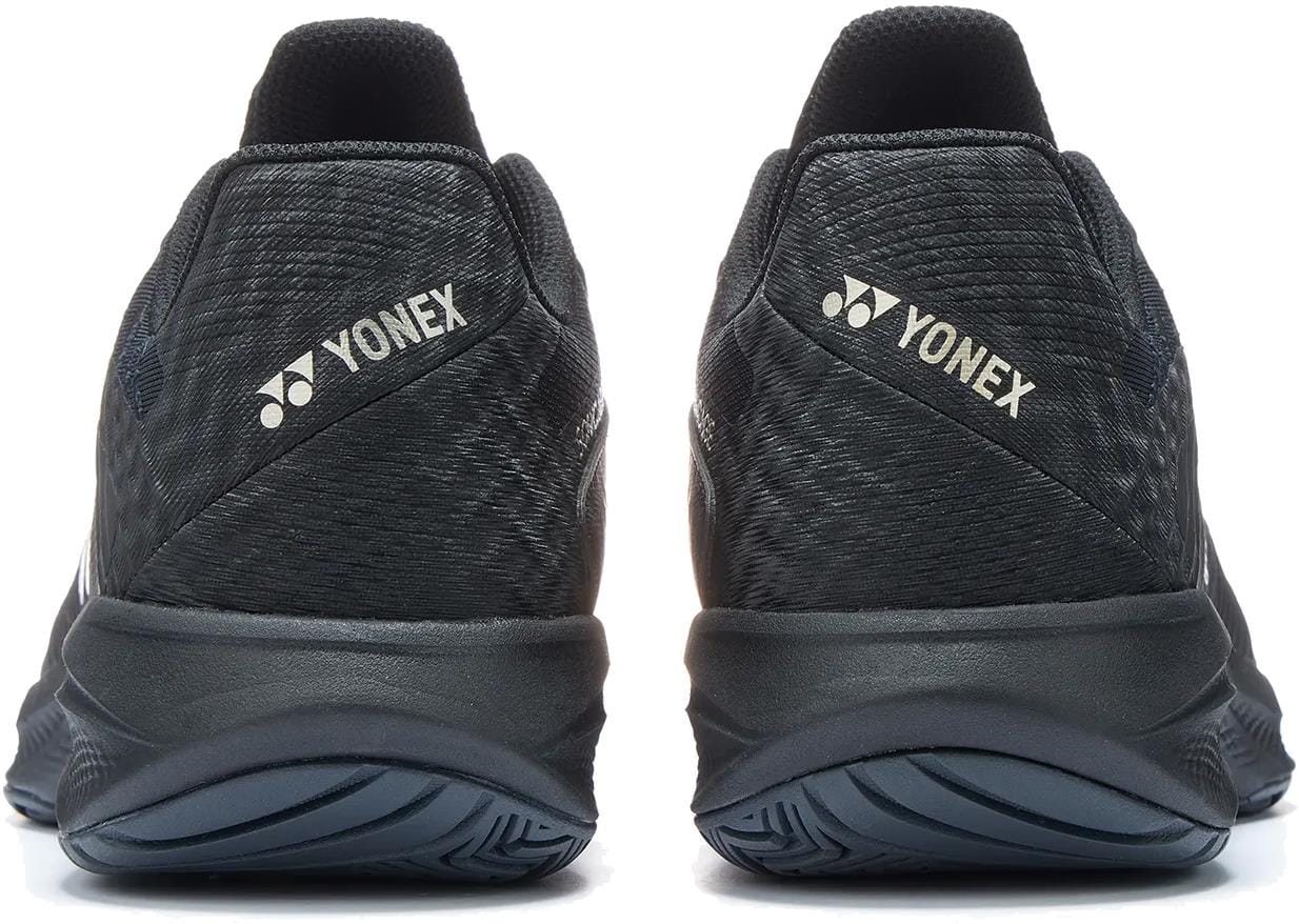 Rear view of Yonex Power Cushion Sonicage Men's Tennis Shoes in Black / Mocha Grey, highlighting the Yonex logo and name on the heel against a white background.