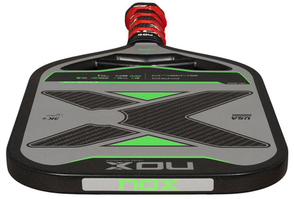 A close-up of the NOX NOV Pro Shield Pickleball Paddle in black and green, featuring Spin Technology, a red and black handle, and bold "NOX" branding on the carbon fibre face.