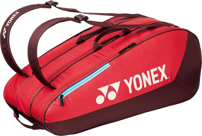 The Yonex 42529EX Team 9 Racket Tennis Bag in ruby red features black zippers, blue accents, and two dark brown straps. The white Yonex logo stands out on the side—ideal for carrying your tennis gear in style.