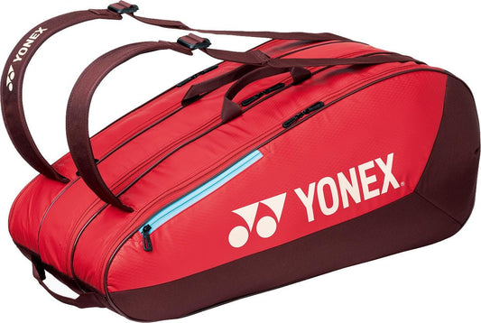 The Yonex 42529EX Team 9 Racket Tennis Bag in ruby red features black zippers, blue accents, and two dark brown straps. The white Yonex logo stands out on the side—ideal for carrying your tennis gear in style.