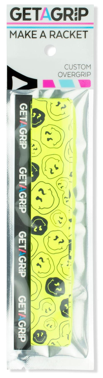 A pack of Get A Grip Tennis Overgrip - Smiley features a bright yellow grip with black cartoon faces, branded with "Get A Grip" and the slogan "MAKE A RACKET"—a fun tennis gift for any player.
