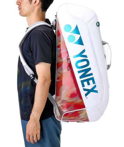 A person stands sideways to the camera with a Yonex 02626EX Expert 6 Racket Tennis Bag - White slung across their back, featuring blue lettering and racket thermoguard.