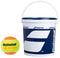 A Babolat Initiation Stage 2 Orange Tennis Ball, featuring a yellow and orange design with "Babolat Orange" branding, sits next to a large white bucket equipped with a blue lid and handle. Ideal for children's training, the bucket prominently showcases the blue and white Babolat logo.