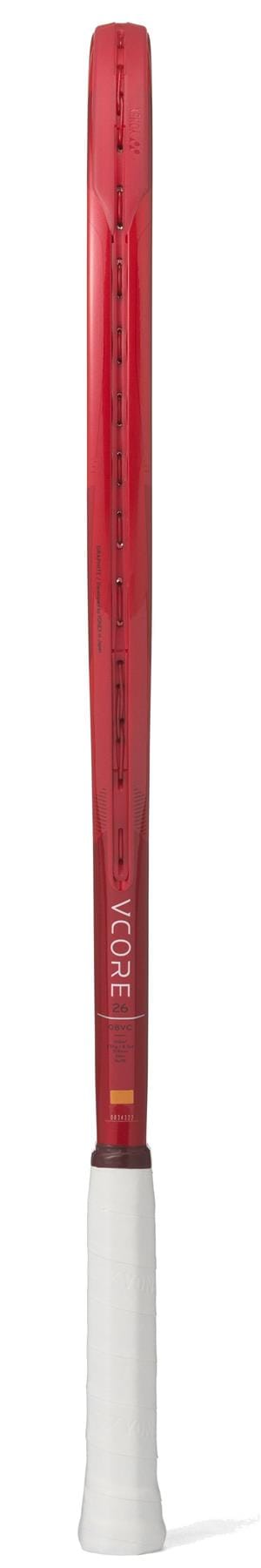A Yonex VCORE 26 Junior Ruby Red 2026 Tennis Racket is shown from the side, featuring a slim frame, white grip handle, visible isometric technology, and the Yonex brand name displayed on the shaft.