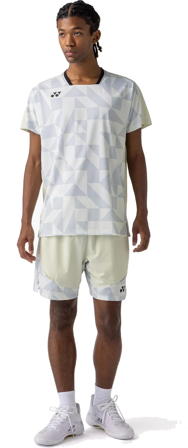 A person faces forward, wearing a Yonex 10712YX Crew Neck Men's Tennis T-Shirt in Champagne, matching shorts, white socks, and white athletic shoes, standing against a plain white background for optimal sports performance.