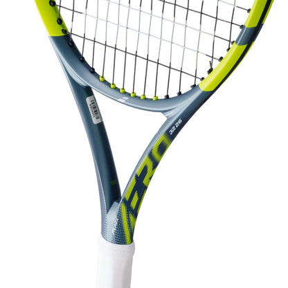 Close-up of the Babolat Pure Aero Junior 26 Tennis Racket 2026 showing its grey, yellow, and black design, spin-focused strings, white grip handle, Babolat branding, and a barcode sticker on the frame.