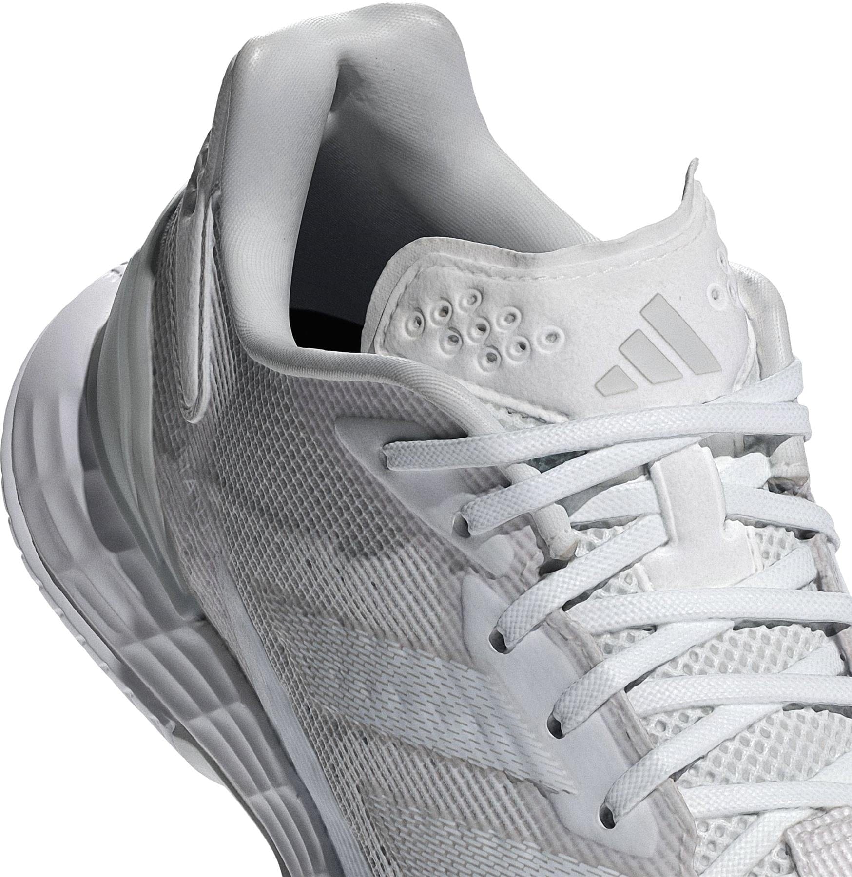 A close-up of the adidas Defiant Speed 2 Women's Tennis Shoes in white, featuring mesh details, white laces, a logo on the tongue, textured sole, and padded collar for comfort. Lightweight design ideal for tennis.
