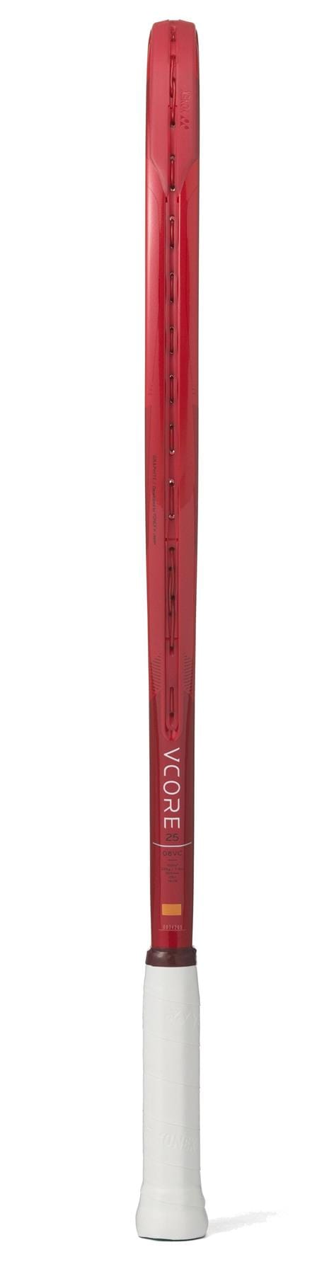 A Yonex VCORE 25 Junior Ruby Red 2026 Tennis Racket with a white grip stands upright, showing only its side profile. "VCORE" is displayed in white on the graphite frame of this Yonex junior racket.