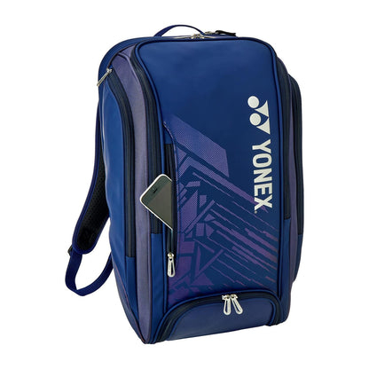 The Yonex 02512EX Expert Tennis Backpack in navy blue features a zippered pocket that fits a smartphone. With geometric purple patterns and sturdy straps, it's perfect for carrying sports equipment at any expert tournament.