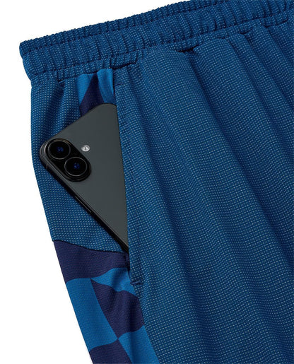 A black smartphone partially tucked into the pocket of Yonex 15240YX Knit Men's Tennis Shorts in indigo blue, featuring a dark blue checkered side pattern and breathable knit fabric.