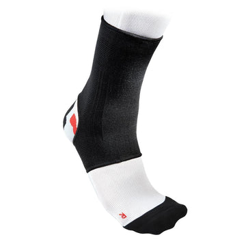 A close-up of a foot showcasing the McDavid 2-Way Elastic Ankle Sleeve in black and white, crafted by McDavid for optimal support and compression. The breathable sleeve snugly fits over the ankle and part of the foot, with a white sock peeking out underneath.