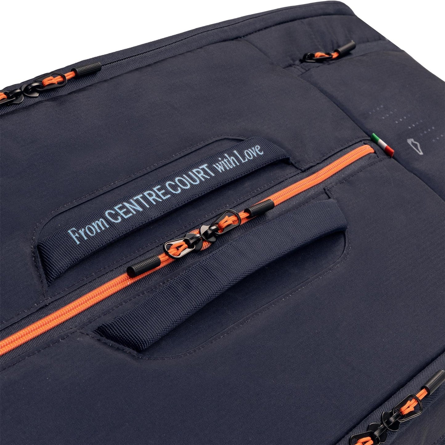 Close-up of the HEAD Pro 12 Racket Tennis Bag XL - Navy by HEAD, featuring orange zippers, black pulls, and a stitched “From CENTRE COURT with Love” label in white—design inspired by Jannik Sinner’s tennis bag.