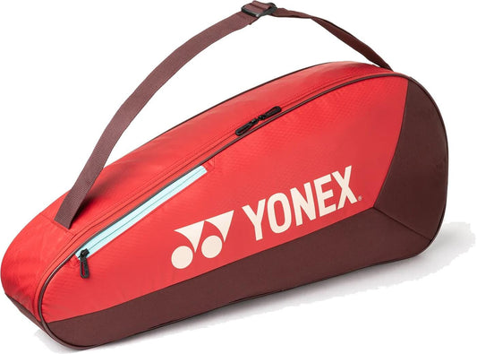 The Yonex 42523EX Team 3 Racket Tennis Bag in Ruby Red is a lightweight bag with a shoulder strap and zipper, fits up to 3 rackets, and features the Yonex logo and branding on the side.