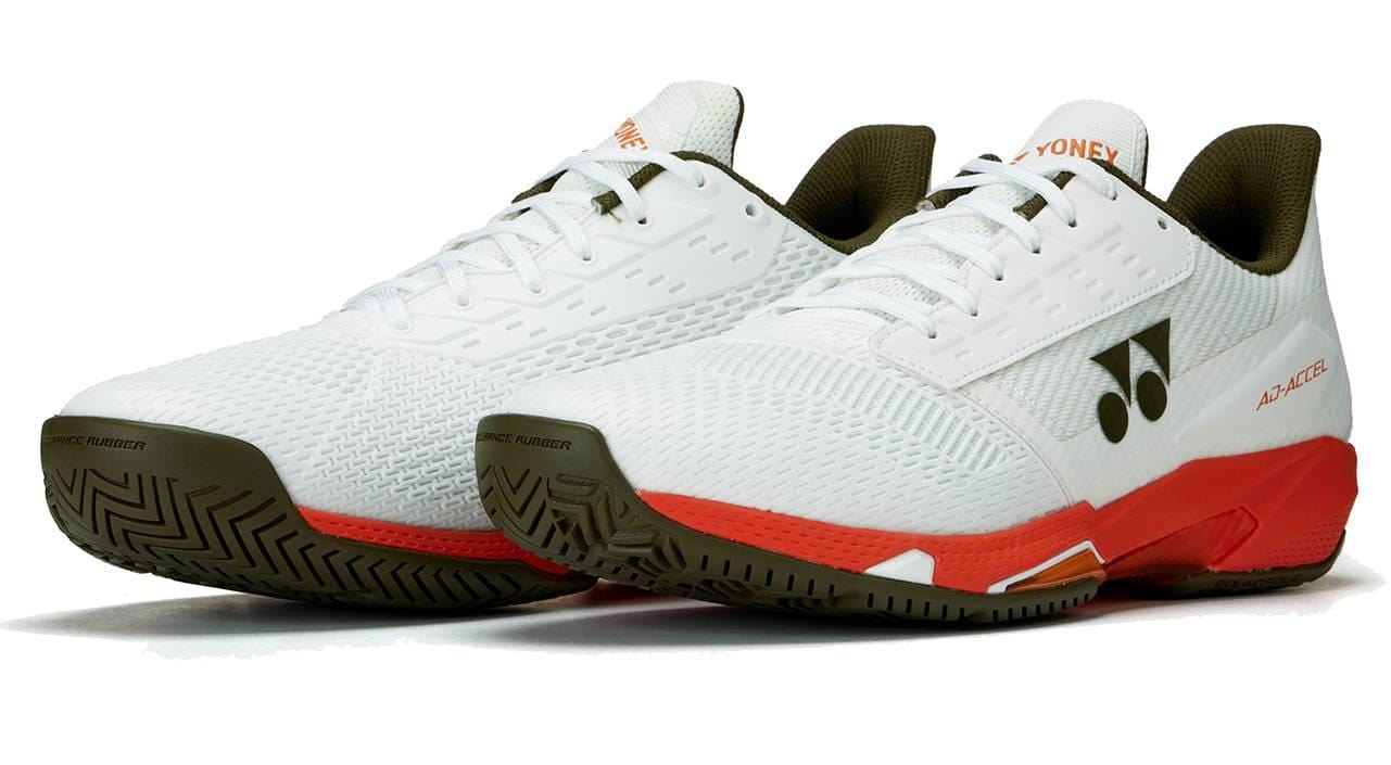 Yonex Power Cushion Ad-Accel Men's Tennis Shoes in white and orange, featuring olive green soles and black Yonex logos, designed for speed on the court, are shown on a plain white background.