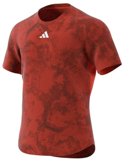 The ADIDAS Paris Men's Freelift Tennis T-Shirt in red, by adidas, boasts a small white triangular logo, short sleeves, and a round neckline. It is ideal for hot weather thanks to its HEAT.RDY technology that helps keep you cool.
