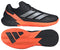 The adidas Defiant Speed 2 Men's Tennis Shoes in black and orange feature silver stripes, orange accents, and a textured orange sole. Side and bottom views showcase their lightweight build, sleek design, and advanced grip pattern.