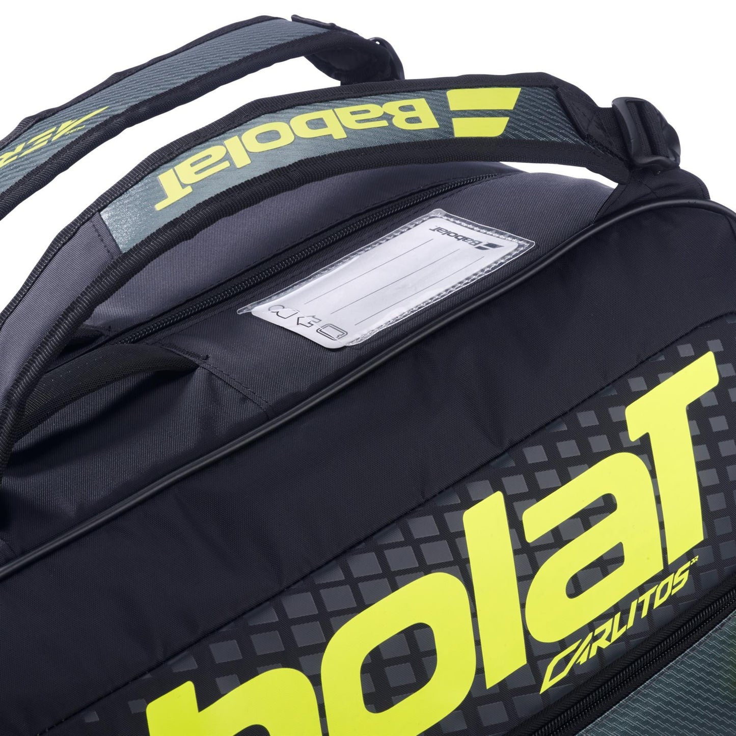 Close-up of the Babolat RH Carlitos Junior 3 Racket Tennis Bag in black/yellow, showing bright yellow branding, padded straps, and a name tag slot with a partially visible card.