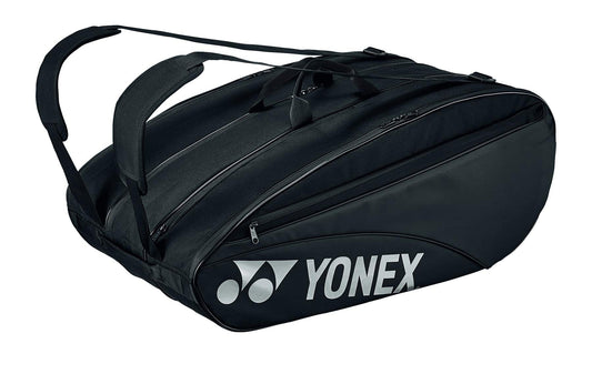 The Yonex 423212EX Team 12 Racket Tennis Bag in black is featured, showcasing a dedicated shoe compartment and multiple gear sections. It has two shoulder straps for easy transport, with the Yonex logo prominently displayed in white on the side.