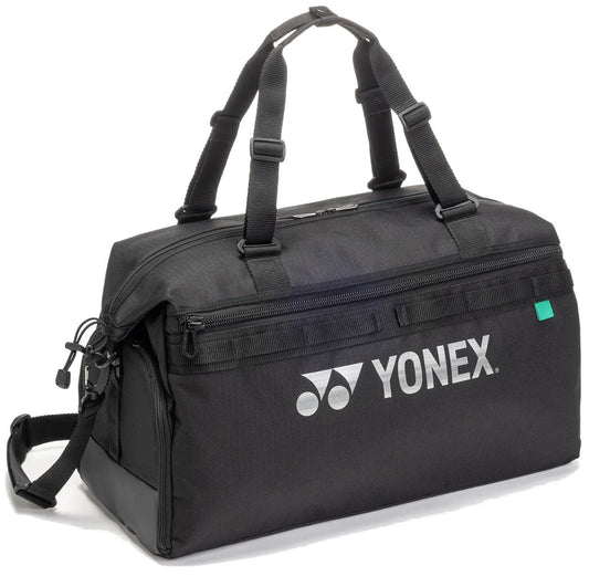 The Yonex BA72611EX Gearlogic Tennis Boston Bag in black features two handles, an adjustable shoulder strap, a front zip pocket, and a white Yonex logo—an ideal versatile duffle tennis bag for all your gear.