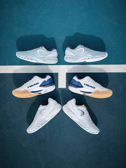 Three pairs of women's tennis shoes are arranged vertically on a blue court, with the HEAD Revolt Pro 5.0 Womens Tennis Shoes - White / Apricot by HEAD featured in the center over a white court line.