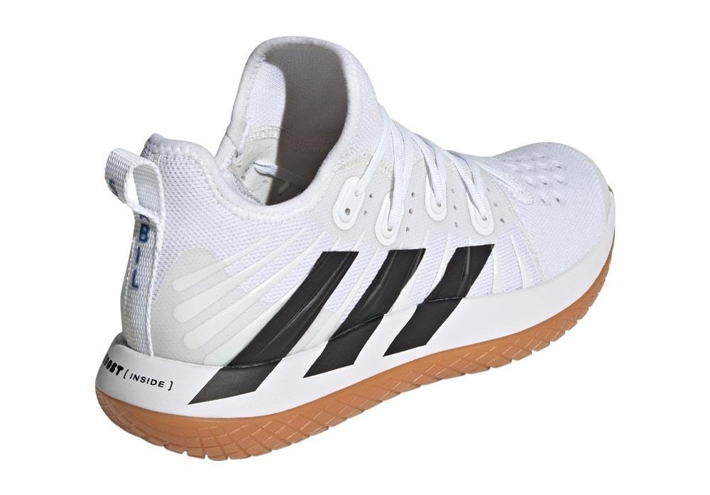 The ADIDAS Stabil Next Gen Primeblue Men's Indoor Shoes, created by adidas, showcase a Cloud White finish with Core Black accents and a brown sole. Ideal for indoor court play, these shoes feature a textured upper and a handy pull tab on the back, offering improved energy return with every step.