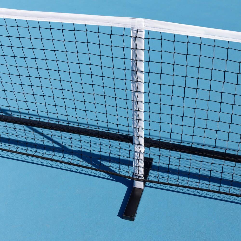A close-up of the HEAD Portable Pickleball Net by HEAD, featuring a white border and durable powder-coated steel frame, set up on a bright blue court with its crisp shadow visible on the ground.