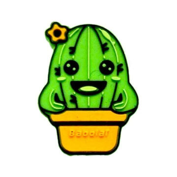 The Babolat Loony Damp Tennis Dampener - Cactus features a cartoon green cactus with a happy face, black eyes, a wide smile, and a small yellow flower on top, sitting in a yellow pot and made by Babolat.
