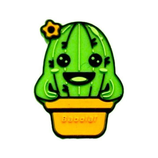 The Babolat Loony Damp Tennis Dampener - Cactus features a cartoon green cactus with a happy face, black eyes, a wide smile, and a small yellow flower on top, sitting in a yellow pot and made by Babolat.