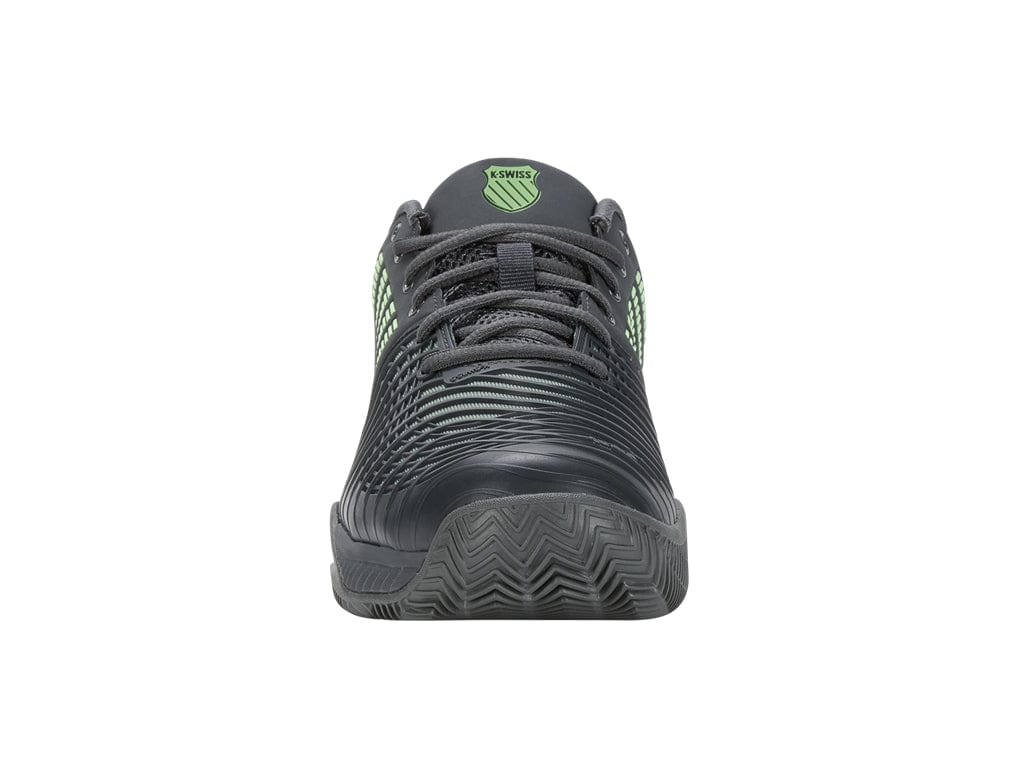 The product showcases a front view of the Sea Spray and Urban Chic athletic tennis shoe by K-Swiss, highlighted with textured detailing in Soft Neon Green. Its design emphasizes on-court performance, featuring a patterned sole ideal for clay court surfaces and laces, along with the K-Swiss logo on the tongue.