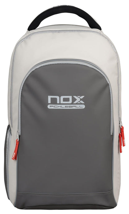 The NOX Pro Pickleball Backpack - Cream features ergonomic padded straps, a spacious front pocket, red zipper pulls, and the "NOX Pickleball" logo displayed on the front.