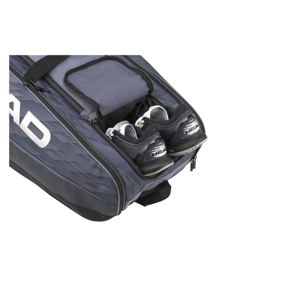 The anthracite and black HEAD Djokovic Monstercombi 12R Tennis Racket Bag, equipped with CCT+ climate control technology, features an open shoe compartment displaying black and white sports shoes. The bold "HEAD" branding mirrors the style favored by champions such as Novak Djokovic.