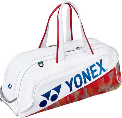 The Yonex 02631WEX Expert Tournament Tennis Bag in white features red handles, blue Yonex logo and name, a subtle red and gold pattern on the bottom edge, plus Thermo Guard technology to protect your gear at tournaments.