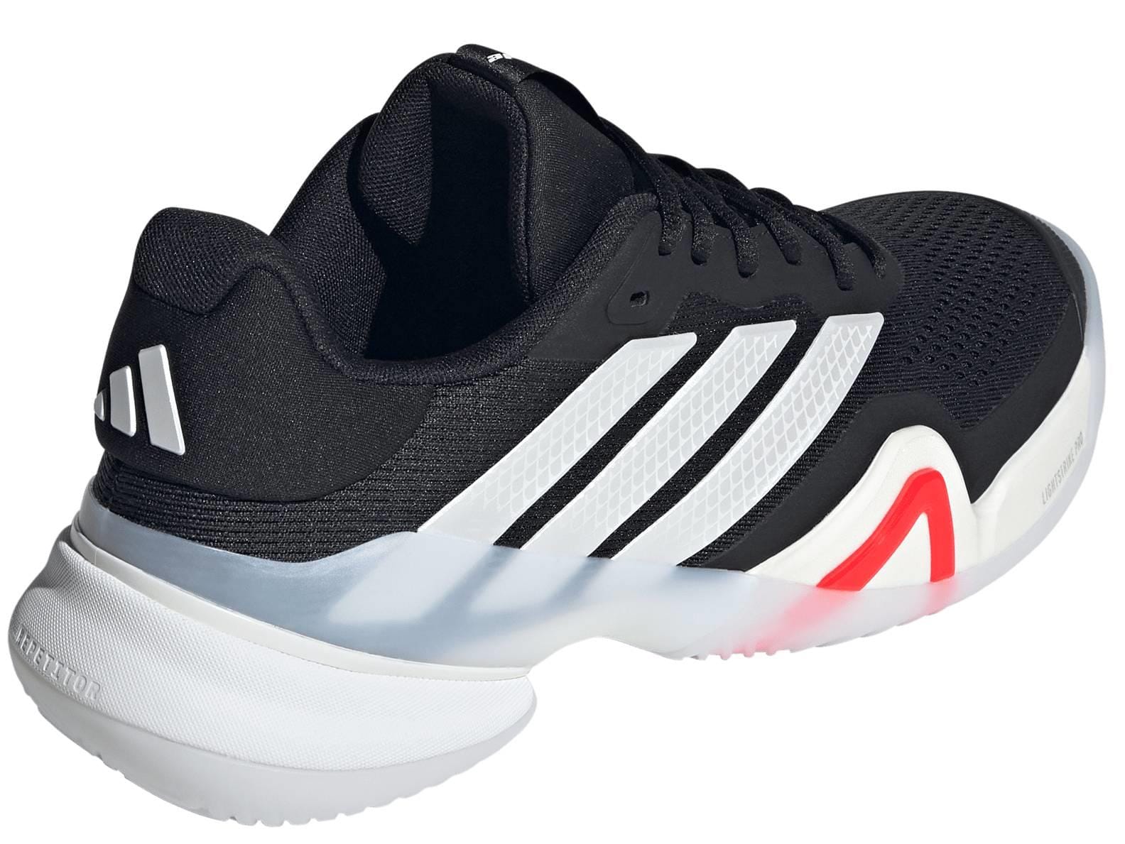 The adidas Barricade 14 Men’s Tennis Shoes in black feature three white stripes, red accents, a textured sole, cushioned heel, and breathable mesh upper—ideal for top performance on the court.
