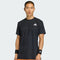 A man in a black adidas Climacool+ Airchill Freelift Mens Tennis T-Shirt and black wristbands stands facing forward against a plain light background, with the adidas logo visible on his moisture-wicking shirt and wristbands.