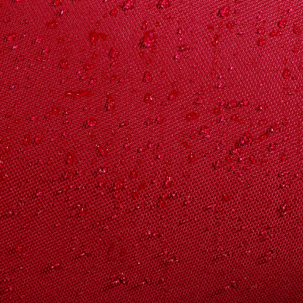 Close-up of burgundy water-resistant fabric on the Babolat Court XS 3 Racket Tennis Bag - Burgundy / Black, with scattered water droplets beading on the surface, highlighting the compact Babolat bag's waterproof texture.