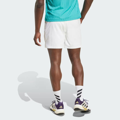 A person wearing a teal shirt, adidas Climacool Ergo Men's Tennis Shorts in white, white socks with black stripes, and purple and white adidas sneakers stands facing away, showing the back of their sporty outfit.